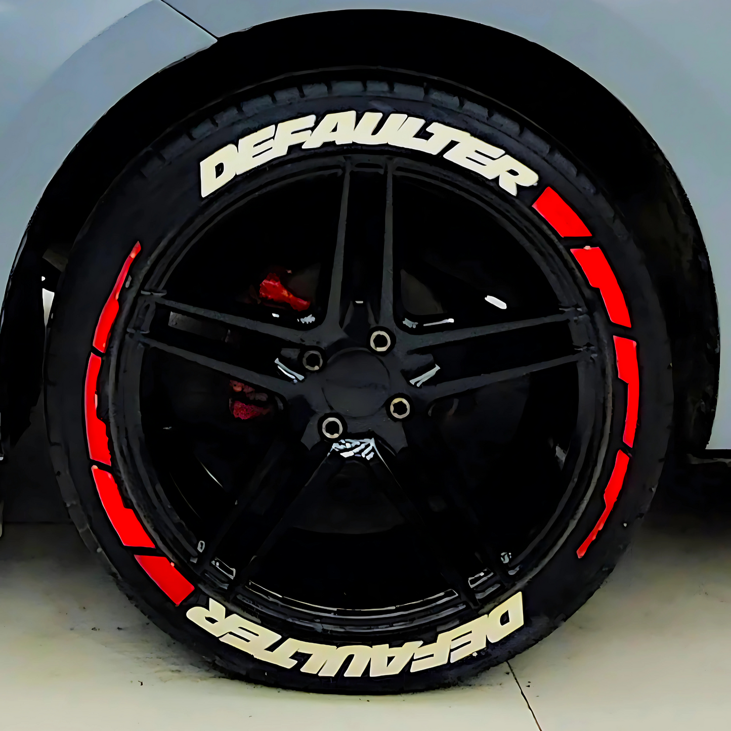 Defaulter car tyre sticker on a black alloy wheel, enhancing vehicle appearance with bold design