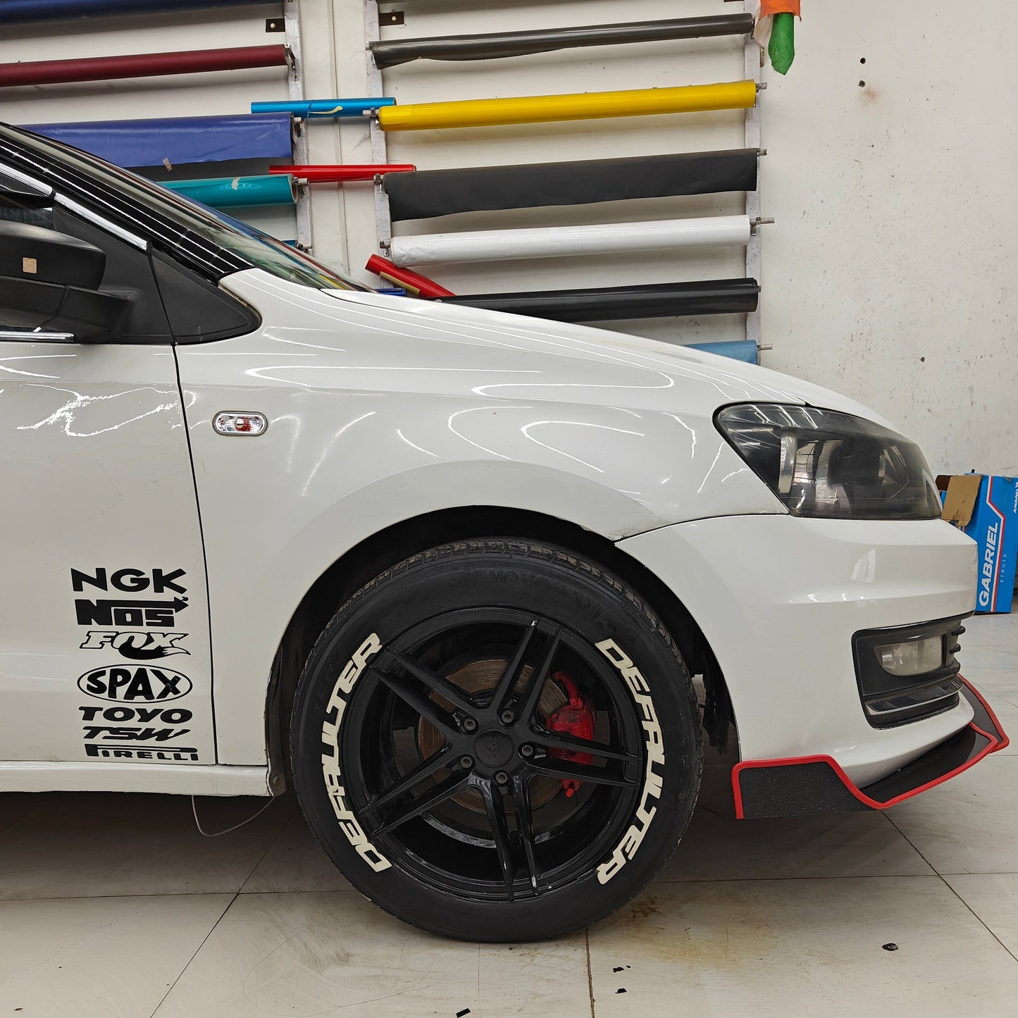 Defaulter tyre sticker on black alloy wheels of a modified white car for automotive enthusiasts