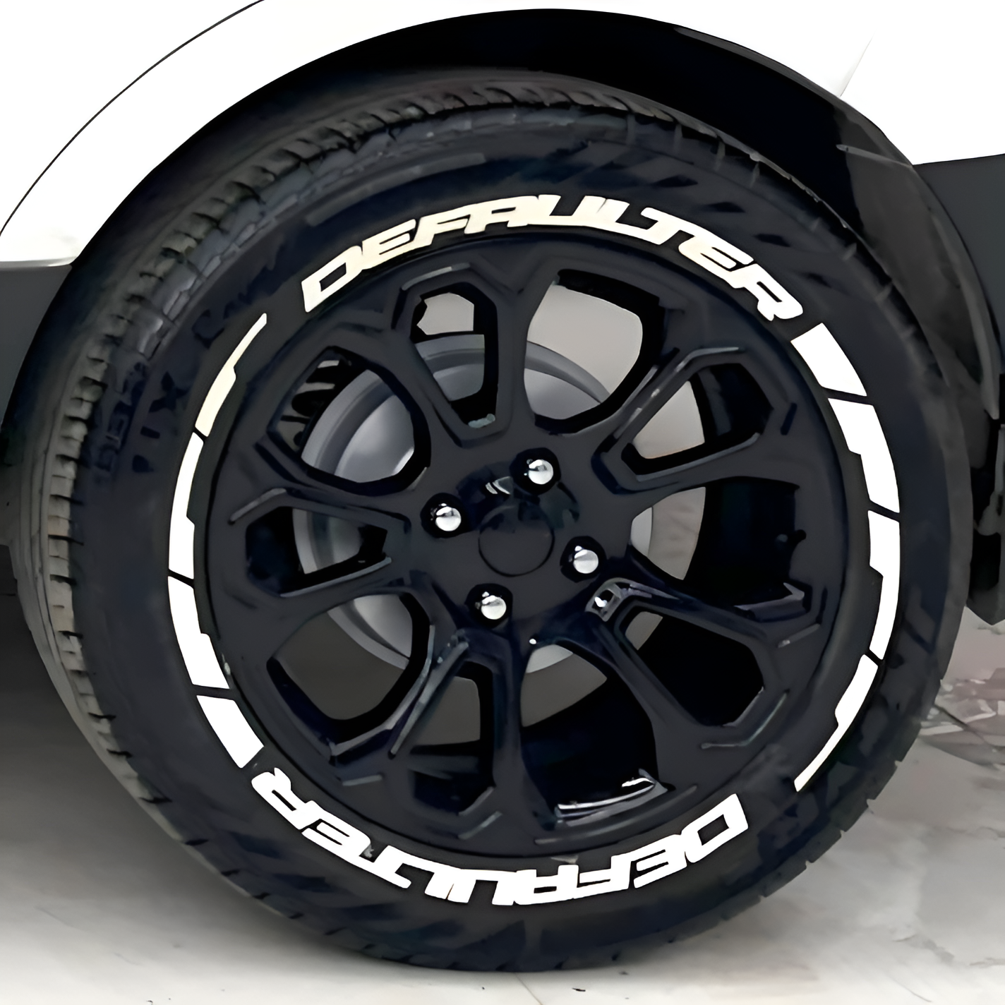 Black alloy wheel featuring DEFAULTER Tyre Stickers for a sporty look