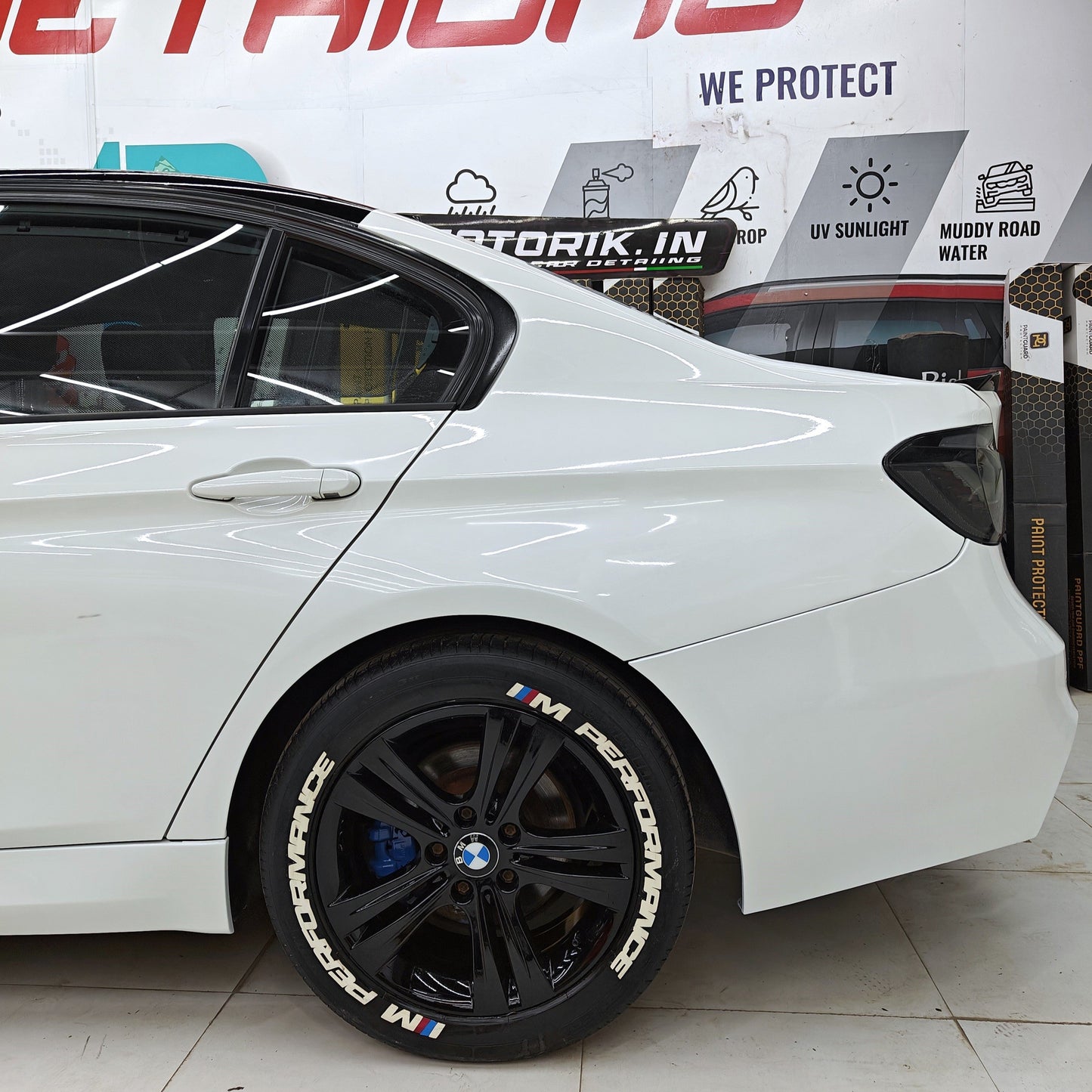 M Performance tire stickers on a black wheel of a white BMW car showcasing stylish detailing