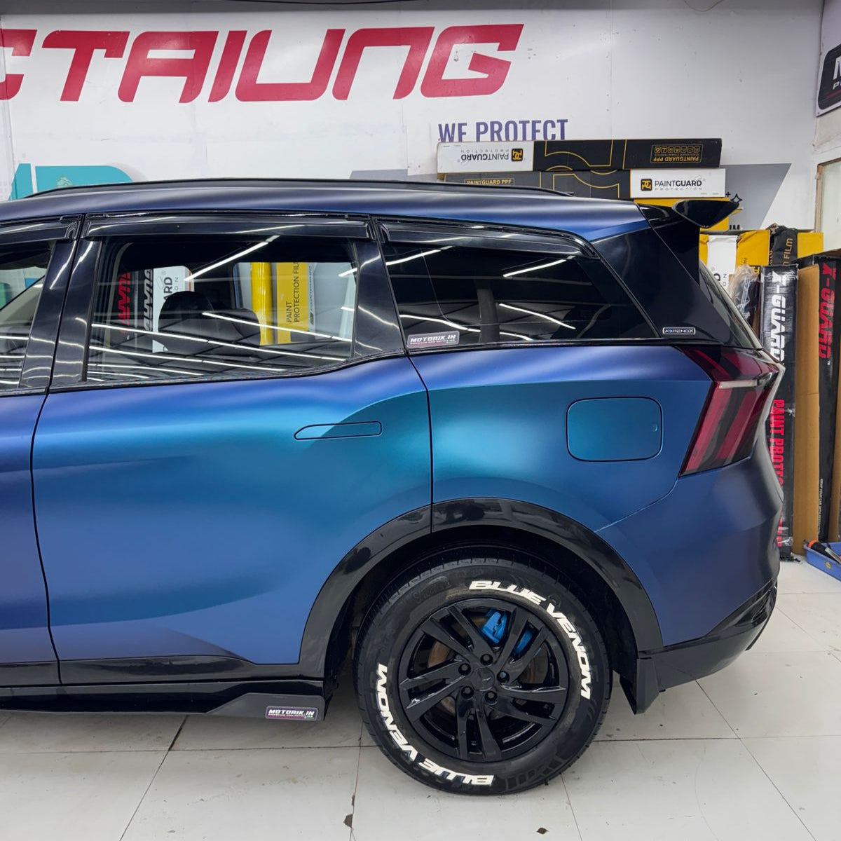 Permanent Tyre Stickers Kit applied on a blue SUV with sporty black rims in a detailing shop