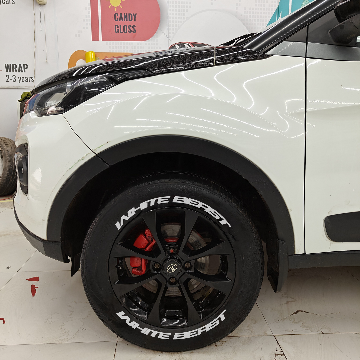 Black alloy wheels featuring White Beast Tyre Stickers on a white vehicle for enhanced style