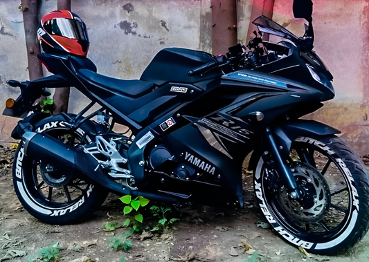Yamaha motorcycle with bike tyre stickers on black tires and red helmet parked outdoors